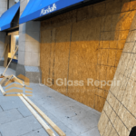 A team of workers installing boards on a large storefront door in a Washington DC property during an emergency board-up.